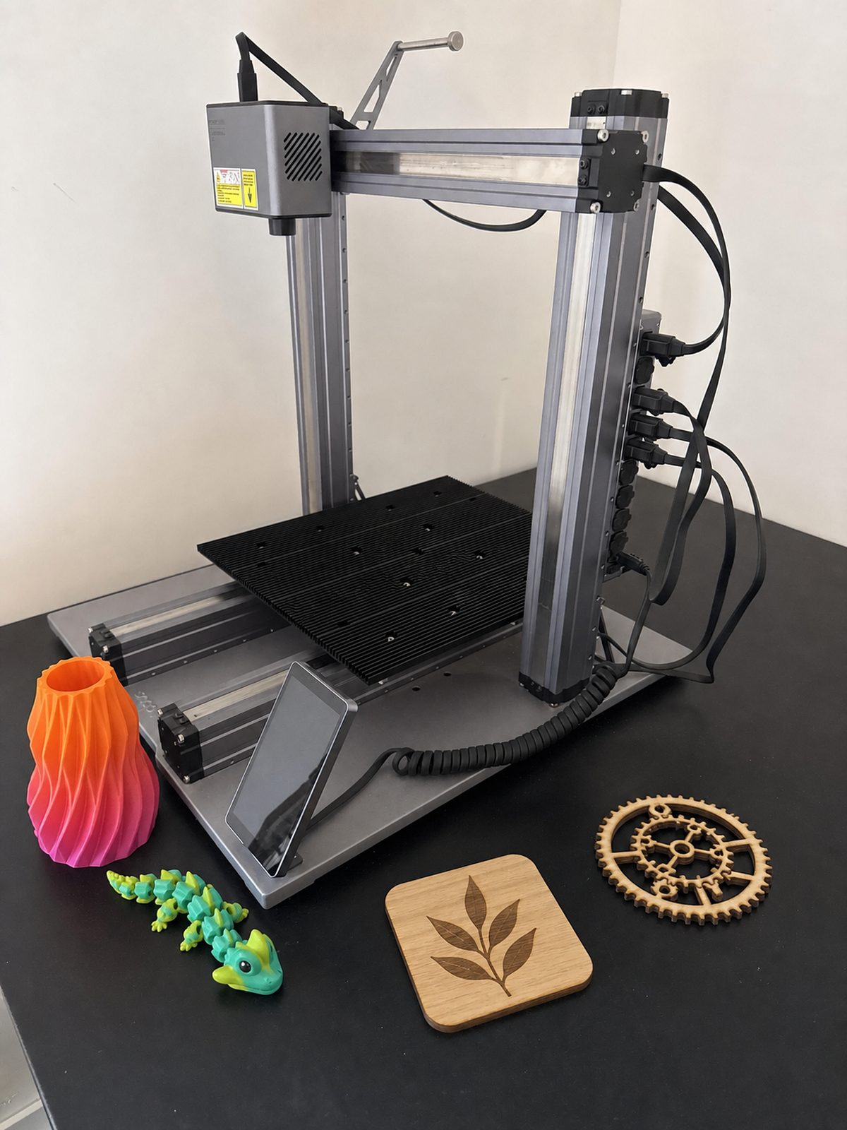 Mijn Snapmaker 3-in-1 met een 3D-geprinte vaas en figuur, een gegraveerde onderzetter en een lasergesneden tandwiel